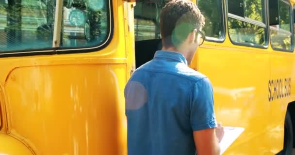 Учитель принимает участие во время посадки студента в автобус — стоковое видео