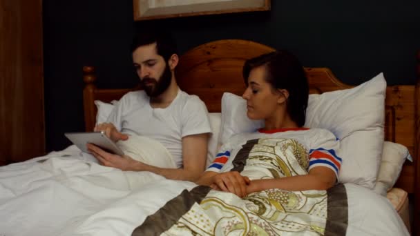 Ζευγάρι χρησιμοποιώντας το tablet στο κρεβάτι στην κρεβατοκάμαρα — Αρχείο Βίντεο
