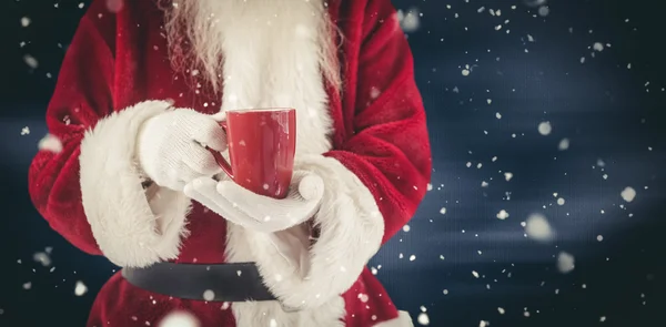 Santa hält eine rote Tasse in der Hand — Stockfoto