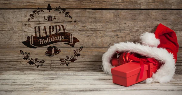 Červené vánoční cetka a dar chovaných v santa hat — Stock fotografie