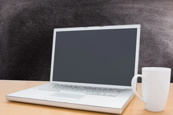 Laptop with coffee mug on chalkboard background — Stock Photo, Image