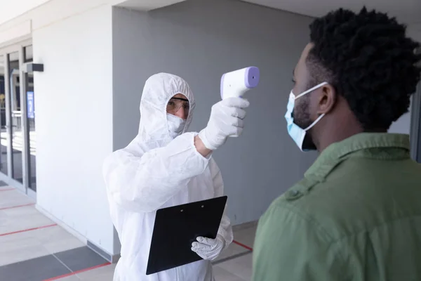 Empresário Afro Americano Tendo Temperatura Tomada Pelo Trabalhador Terno Protetor — Fotografia de Stock