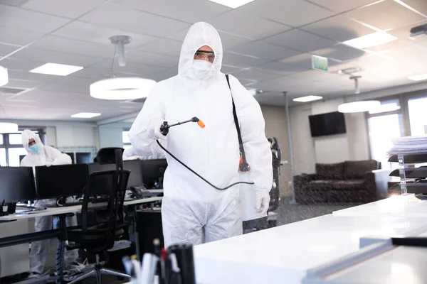 穿着防护服 面罩和手套的工人使用抗菌消毒剂喷剂清洁办公室 Coronavirus Covid 19大流行病期间工作场所的卫生 — 图库照片