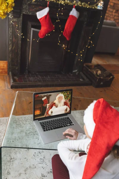 在圣诞节的时候 白人妇女在装饰过的壁炉旁 用笔记本电脑 与圣诞老人聊天的视频 呆在家里 Covid期间的社会疏离 — 图库照片