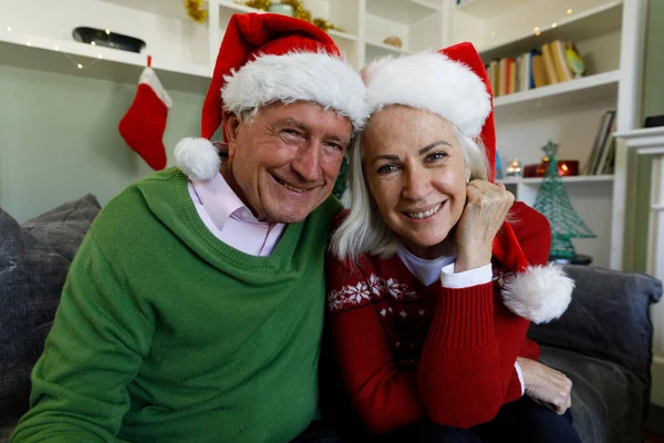 Retrato Pareja Mayor Sombreros Santa Sonriendo Mientras Sienta Sofá Casa — Foto de Stock