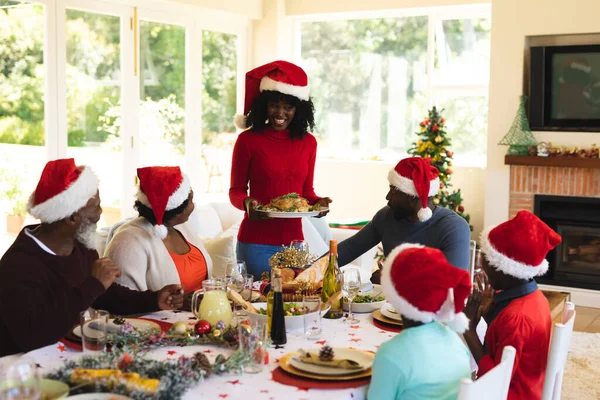 Família Várias Gerações Vestindo Chapéus Papai Noel Almoçando Juntos Enquanto — Fotografia de Stock