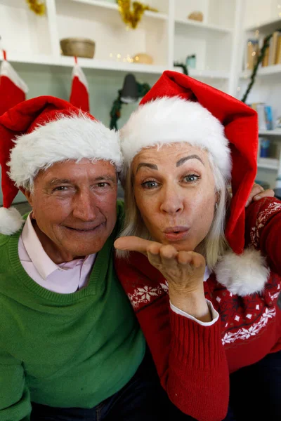 Retrato Casal Sênior Chapéus Papai Noel Sentado Sofá Soprando Beijos — Fotografia de Stock