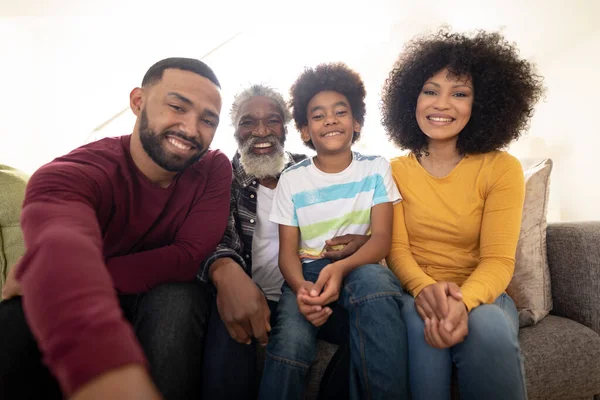 Portrait of multi generation African American family at home sitting on sofa in living room, smiling to camera. Family spending quality time at home together in slow motion.