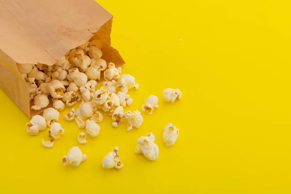 高角度的爆米花从黄色背景的褐色纸袋中溢出 有趣的聚会食物甜食小吃抄袭空间概念 — 图库照片