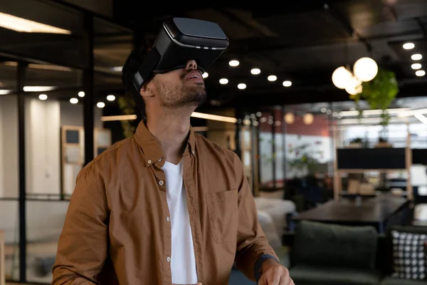 stock image Mixed race businessman wearing virtual reality headset in creative office. technology and social distancing in business office workplace during covid 19 coronavirus