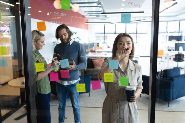 創造的なオフィスで働くビジネスの人々の多様なグループ 人々がブレインストーミングをしてガラス板にメモを取ります ビジネス関係者や職場の同僚が — ストック写真