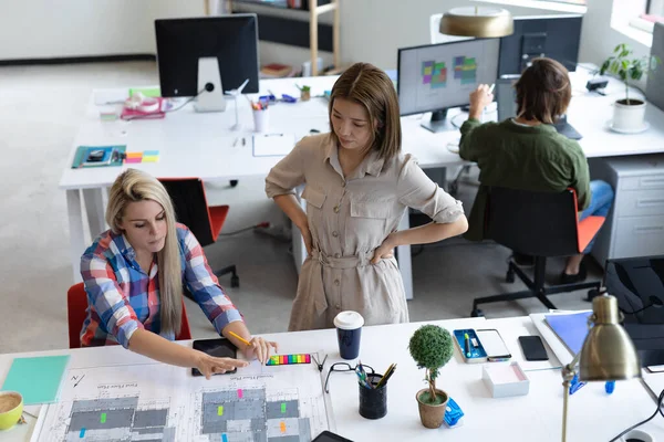 Twee Verschillende Zakenvrouwen Kijken Naar Blauwdrukken Discussiëren Creatief Kantoor Zakenmensen — Stockfoto