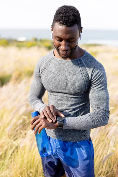 Portrait Fit African American Man Sportswear Using Smartwatch Holding Water — Zdjęcie stockowe