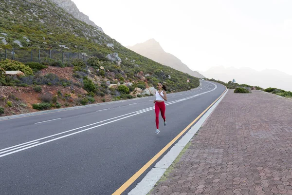 Ajuste Mujer Afroamericana Ropa Deportiva Corriendo Una Carretera Costera Mirando —  Fotos de Stock