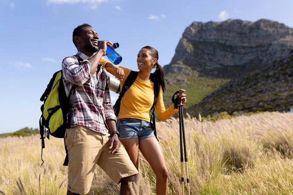 Fit African American Couple Wearing Backpacks Nordic Walking Poles Drinking — Zdjęcie stockowe