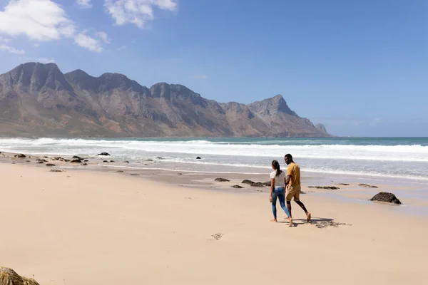 アフリカ系アメリカ人のカップルが海沿いのビーチで手をつないで歩いている 健康的なライフスタイル自然レジャー — ストック写真