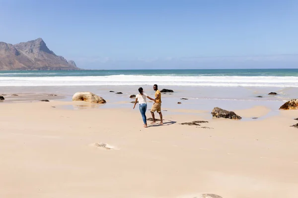 アフリカ系アメリカ人のカップルが海沿いのビーチで手をつないで歩いている 健康的なライフスタイル自然レジャー — ストック写真