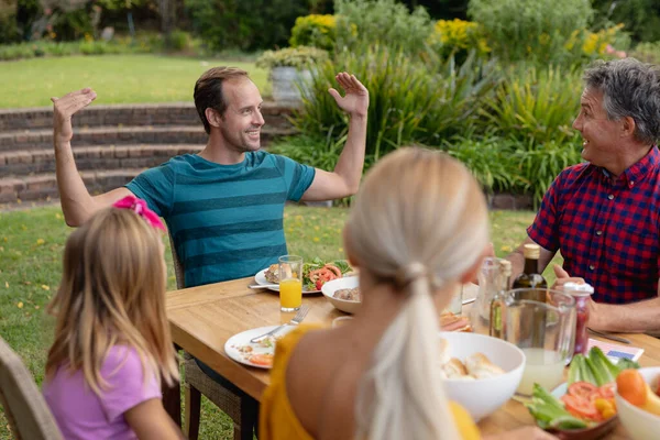 Biały Mężczyzna Siedzący Przy Stole Rozmawiający Rodziną Jedzącą Posiłek Ogrodzie — Zdjęcie stockowe