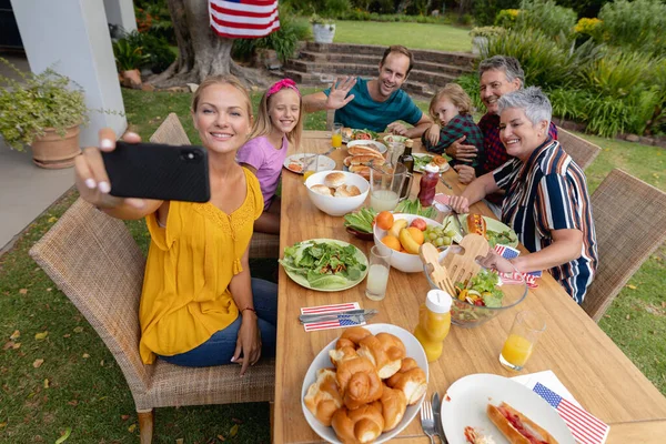 Biała Kobieta Robi Sobie Selfie Trójpokoleniową Rodziną Jedząc Posiłek Ogrodzie — Zdjęcie stockowe
