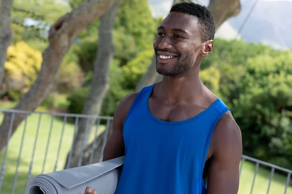 Hombre Afroamericano Sosteniendo Esterilla Yoga Sonriendo Soleada Terraza Del Jardín —  Fotos de Stock