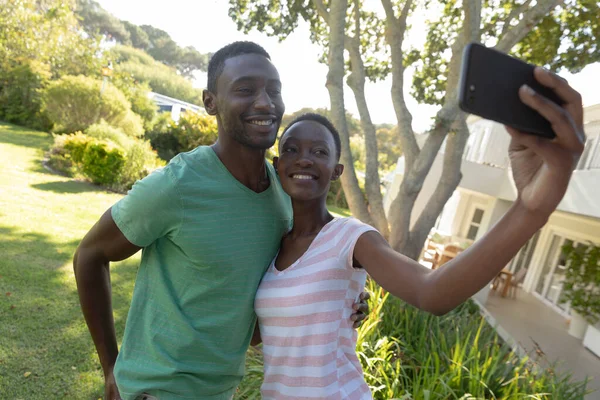 アフリカ系アメリカ人のカップルは日当たりの良い庭のテラスで自撮りをしています 隔離されたまま家にいると — ストック写真
