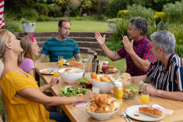 Homem Idoso Caucasiano Sentado Mesa Falar Com Família Comer Jardim — Fotografia de Stock
