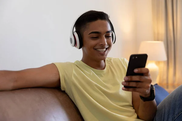 Homem Raça Mista Sentado Sofá Usando Fones Ouvido Sorrindo Usando — Fotografia de Stock