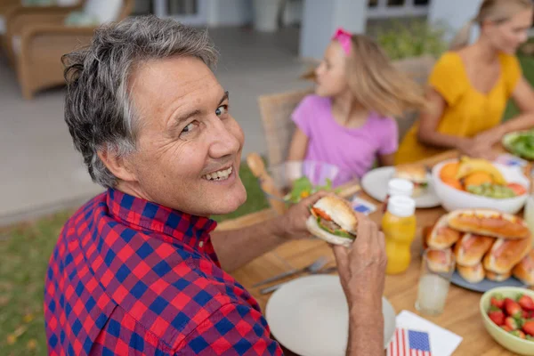 Sonriente Hombre Mayor Caucásico Sosteniendo Hamburguesa Con Comida Familiar Juntos — Foto de Stock