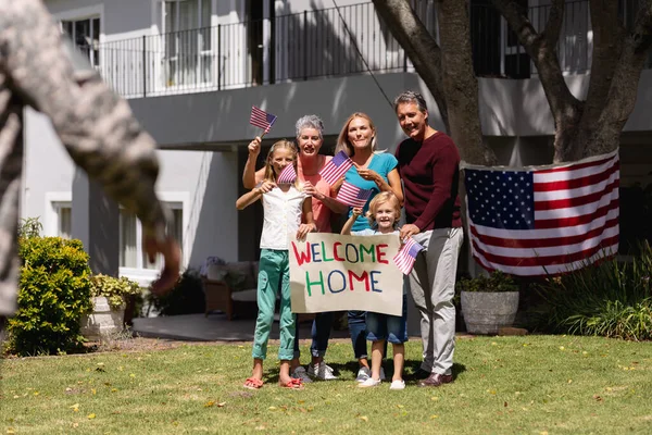 白人兵士の父と家族は歓迎の印とアメリカの旗を持って家の外で会う 兵士は家族の元に戻り — ストック写真
