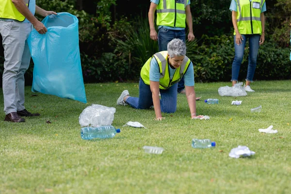 Mulher Idosa Caucasiana Com Grupo Voluntário Ajoelhado Coletando Lixo Campo — Fotografia de Stock