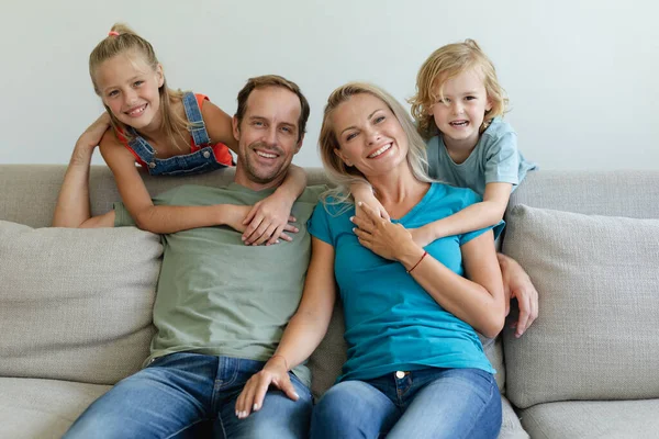 Portrait Smiling Caucasian Parents Sitting Couch Son Daughter Embracing Them — Stock Photo, Image