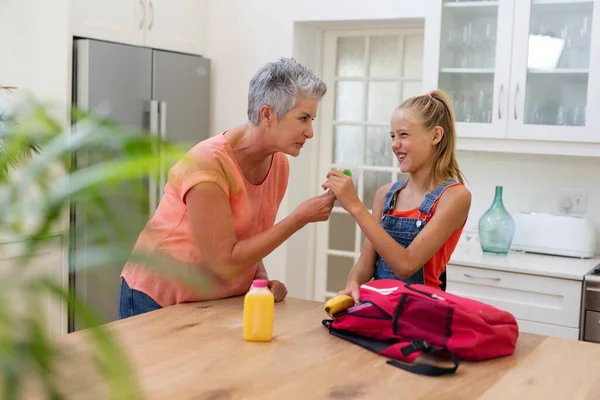 Senior Grandmother Giving Granddaughter Packed Lunch Lollipop Kitchen Happy Family — Stock Photo, Image