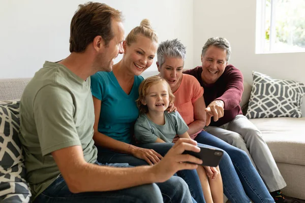白人の父親は妻 息子と一緒にソファに座ってスマートフォンを見ていました 幸せな3世代の家族が家で一緒に過ごす時間 — ストック写真