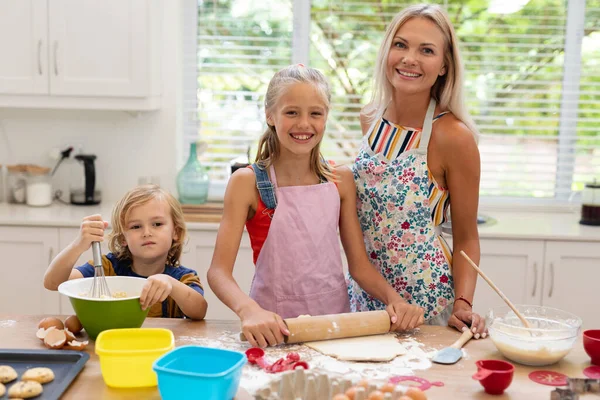 Gülümseyen Beyaz Anne Kız Oğul Önlük Giyip Mutfakta Kurabiye Pişiriyorlar — Stok fotoğraf