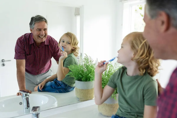 在浴室里笑着的高加索祖父 孙子刷牙都照镜子 隔离检疫期间单独呆在家里 — 图库照片