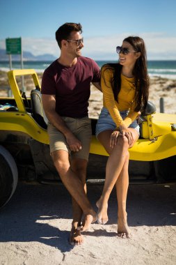 Happy caucasian couple sitting on beach buggy by the sea embracing. beach break on summer holiday road trip. clipart