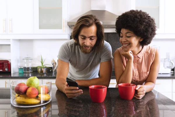 Happy Diverse Couple Standing Kitchen Drinking Coffee Using Smartphone Staying — Stock Photo, Image