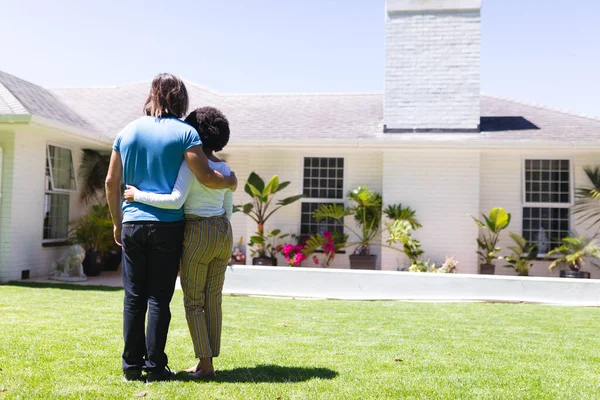 Diversa Pareja Abrazándose Frente Casa Terraza Soleada Del Jardín Permanecer — Foto de Stock