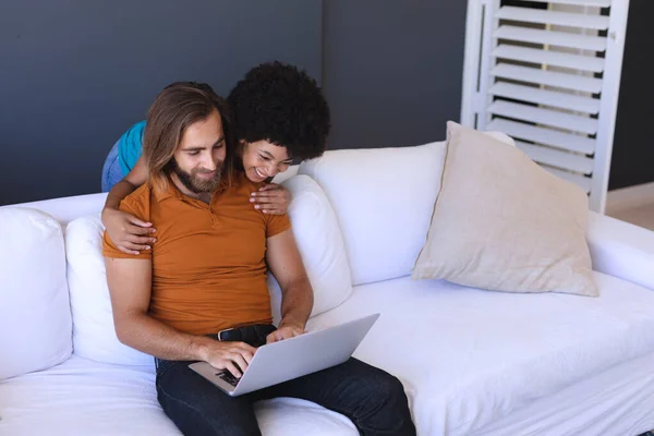 Feliz Pareja Diversa Sentada Sofá Abrazando Utilizando Ordenador Portátil Permanecer —  Fotos de Stock