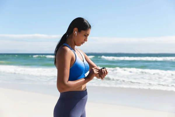 Mieszana Kobieta Wyścigowa Ćwicząca Plaży Bezprzewodowymi Słuchawkami Pomocą Smartwatcha Zdrowy — Zdjęcie stockowe