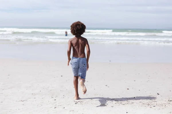 海岸を走っているアフリカ系アメリカ人の少年の後部ビュー 旅行休暇夏のビーチコンセプト — ストック写真