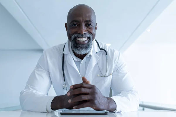 Sonriendo Afroamericano Médico Masculino Sentado Escritorio Con Tableta Que Consulta — Foto de Stock