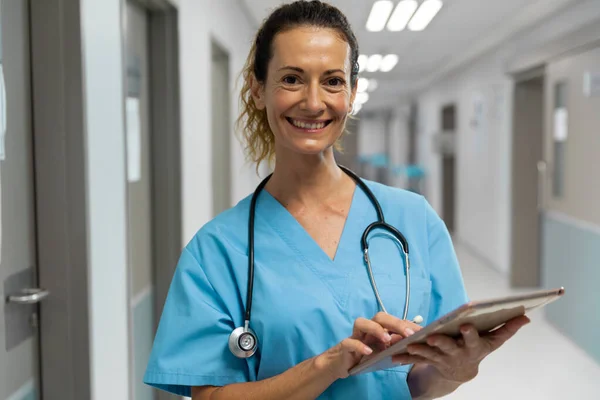 Portrait Mixed Race Female Doctor Standing Corridor Smiling Using Laptop — Stock fotografie