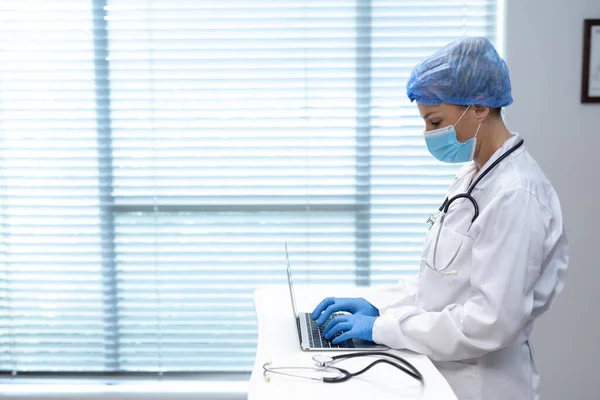 Hastanede Dizüstü Bilgisayar Kullanarak Yüz Maskesi Takan Beyaz Kadın Doktor — Stok fotoğraf