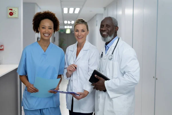 病院の廊下に立っている3人の多様な男性と女性の医師の肖像画がカメラに微笑んだ コロナウイルスにおける医療 医療サービス Covid 19パンデミック — ストック写真