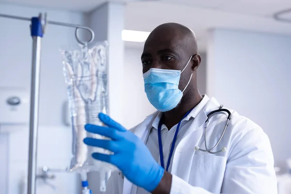 アフリカ系アメリカ人男性医師の顔マスクと手袋を着用病院病棟でIv点滴バッグを準備 コロナウイルスにおける医療 医療サービス Covid 19パンデミック — ストック写真