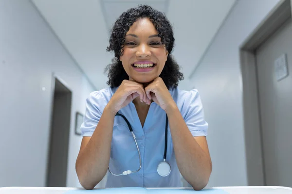 Mieszany Wyścig Kobiet Lekarz Przy Biurku Opierając Podbródek Rękach Uśmiechając — Zdjęcie stockowe