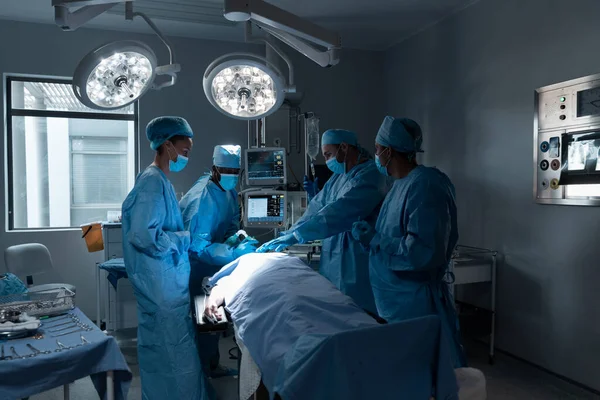 手術室で顔のマスクと外科手術の全体を身に着けている多様な男性と女性の医師 コロナウイルスにおける医療 医療サービス Covid 19パンデミック — ストック写真