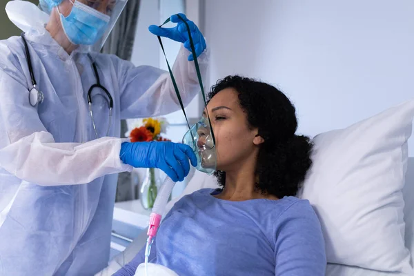 Doctora Caucásica Traje Ppe Poniendo Ventilador Paciente Afroamericana Medicina Salud —  Fotos de Stock