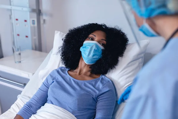 フェイスマスクを着用してベッドで女性患者を慰め顔マスクで病院で白人女性医師 コロナウイルス感染症の治療に従事する医療従事者は — ストック写真